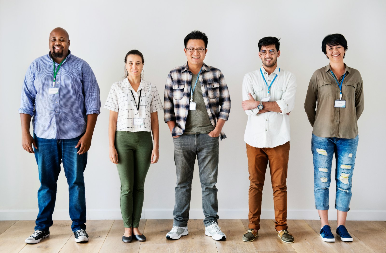 Five colleagues standing side by side against a white wall.